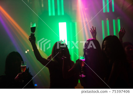 Silhouette image of people dance in disco night club to music from DJ on stage 75397406