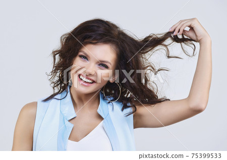 attractive girl with a smile holds her hand in her hair 75399533