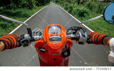 Scooter road trip. POV view, first person. Men on red motorbike in white clothes on drive forest road trail. Hold the steering wheel motorbike. Scooter road trip. POV view, first person. Men on red motorbike in white clothes on drive forest road trail. Hold the steering wheel motorbike. 75399657