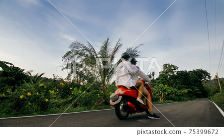 Love couple on red motorbike in white clothes to go on forest road trail trip. Two caucasian tourist woman man drive on scooter. Motorcycle rent. 75399672