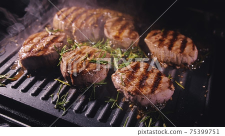 Delicious juicy meat steak cooking on grill. Prime beef fry on electric roaster, rosemary, black pepper, salt. Slow motion. 75399751