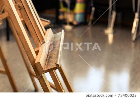 Close up of empty old stained wooden easel tripod for painting frame and canvas in the studio 75400022