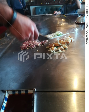 在您面前燒烤的沖繩牛排店在燒烤時切肉 在您面前燒烤的沖繩牛排店在燒烤時切肉 75400112