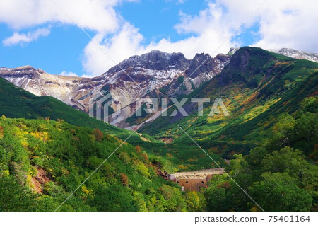 Mount Kamihorokametoku seen from the observatory at Tokachidake Onsen in Hokkaido (first snowfall and autumn leaves) 75401164