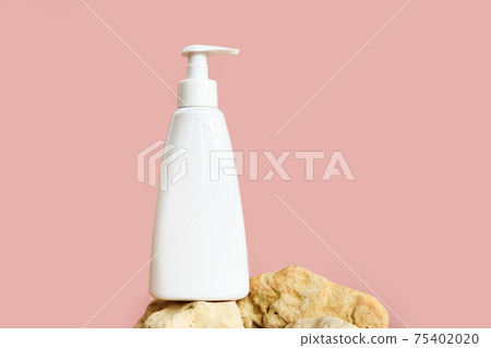 Unbranded white pump cream bottle on rock isolated on light pink background, cosmetic packaging mockup with copy space. Template, front view. Liquid soap or cleansing cream bottle. Unbranded white pump cream bottle on rock isolated on light pink background, cosmetic packaging mockup with copy space. Template, front view. Liquid soap or cleansing cream bottle. 75402020