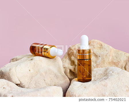 Two bottles of hyaluronic acid with pipette on stone. Essential oil for care of skin. Mockup. Two bottles of hyaluronic acid with pipette on stone. Essential oil for care of skin. Mockup. 75402021
