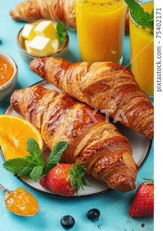 Fresh sweet croissants with butter and orange jam for breakfast. Continental breakfast on a bright concrete table Fresh sweet croissants with butter and orange jam for breakfast. Continental breakfast on a bright concrete table 75402171