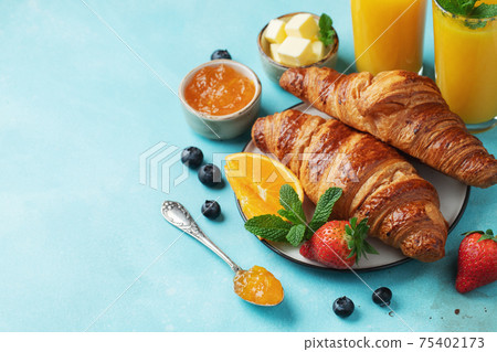 Fresh sweet croissants with butter and orange jam for breakfast. Continental breakfast on a bright concrete table. Top view with copy space. Flat lay 75402173