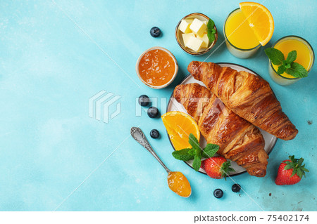 Fresh sweet croissants with butter and orange jam for breakfast. Continental breakfast on a bright concrete table. Top view with copy space. Flat lay 75402174