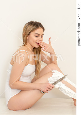 Woman shaving legs with knife Woman shaving legs with knife 75402188