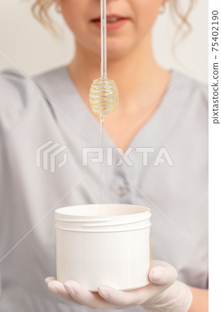 Beautician holding bowl with wax Beautician holding bowl with wax 75402190