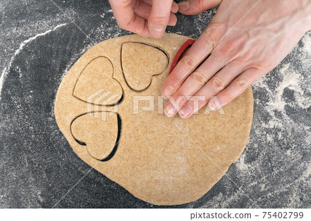 Women hands making heart shaped dough. Process of making shortbread cookies Women hands making heart shaped dough. Process of making shortbread cookies 75402799