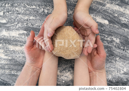 Mom and two children are holding dough. Mom cooks with the children. Mom and two children are holding dough. Mom cooks with the children. 75402804