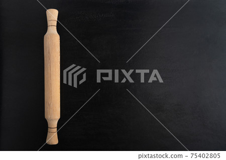 Wooden rolling pin on black background, top view. Copy spac. Kitchen concept Wooden rolling pin on black background, top view. Copy spac. Kitchen concept 75402805
