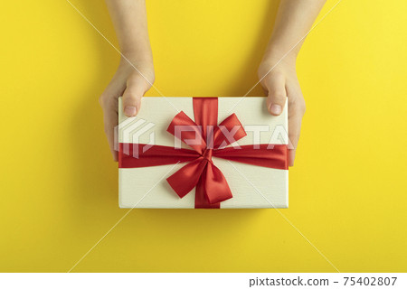 Childrens hands are holding gift on yellow background. Top view. Childrens hands are holding gift on yellow background. Top view. 75402807