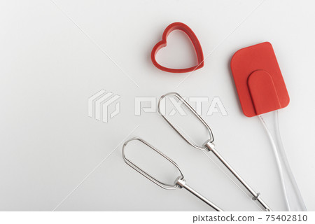 Mixer whisk, kitchen silicone spatula and heart-shaped cookie cutter, white background. Mixer whisk, kitchen silicone spatula and heart-shaped cookie cutter, white background. 75402810
