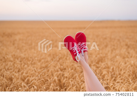Feet in red shoes funny sticking out of wheat field. be yourself 75402811