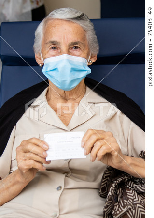 Senior woman holding her vaccination certificate after getting the Covid-19 vaccine at a vaccination site in Colombia. Authentic vaccination. Real patient 75403149