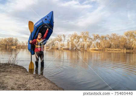 happy senior male  paddler with an inflatable packraft 75403440