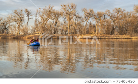 senior male  is paddling an inflatable packraft 75403450