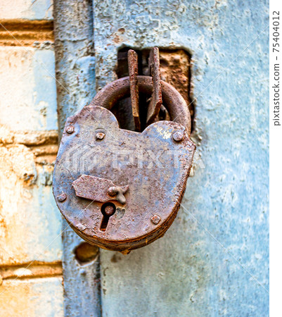 Rusty padlock on an old metal door 75404012