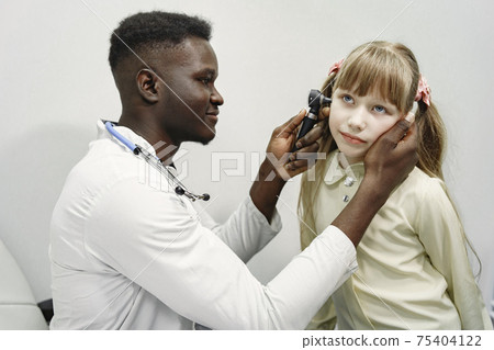 African doctor examines a girl in the ward near couch African doctor examines a girl in the ward near couch 75404122