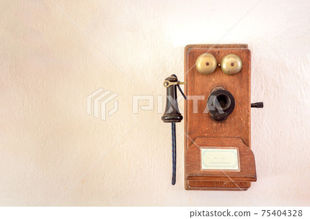 An old wall telephone of the early 20th century on the wall. An old wall telephone of the early 20th century on the wall. 75404328