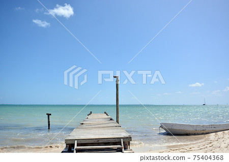 Wooden pier with blue sea and blue sky on background. Wooden pier with blue sea and blue sky on background. 75404368