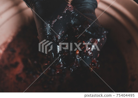 Winemaking at home, squeezing grape juice by hand, the natural fermentation process. Winemaking at home, squeezing grape juice by hand, the natural fermentation process. 75404495
