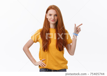 Portrait of happy young woman standing isolated over white wall background. Looking camera showing copyspace pointing 75405744