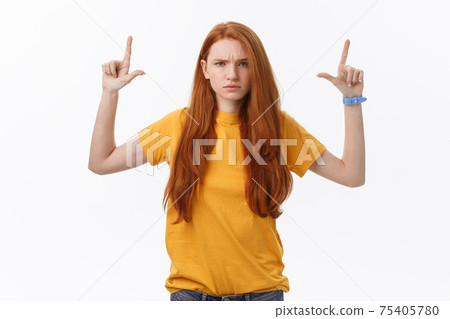 Portrait of happy young woman standing isolated over white wall background. Looking camera showing copyspace pointing 75405780