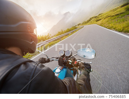 Motorcycle driver riding on mountain highway, handlebars view Motorcycle driver riding on mountain highway, handlebars view 75406885