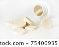 A plastic bottle with several pills 75406935