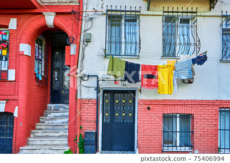 Usual life. The multicolored clothes dry on the rope. A picturesque old district in Istanbul. Low rise colorful houses and narrow cozy streets Usual life. The multicolored clothes dry on the rope. A picturesque old district in Istanbul. Low rise colorful houses and narrow cozy streets 75406994