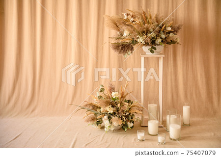 Decorations from dry beautiful flowers in a white vase on a beige fabric background Decorations from dry beautiful flowers in a white vase on a beige fabric background 75407079