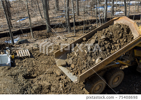 Road construction highway road on dump truck dumps its load of rock and soil Road construction highway road on dump truck dumps its load of rock and soil 75408698