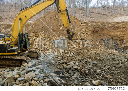 Excavator clearing rock and soil for new road construction site Excavator clearing rock and soil for new road construction site 75408712