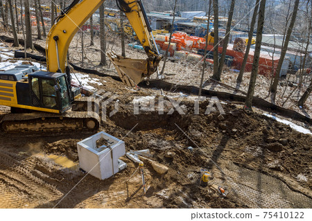Worker construction excavation water drainage at road construction site the square concrete manholes installed for draining Worker construction excavation water drainage at road construction site the square concrete manholes installed for draining 75410122