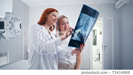 Female doctor assuring female patient in good X ray results 75414908