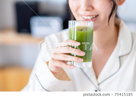 A young woman drinking green juice A young woman drinking green juice 75415185