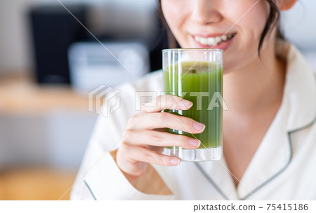 A young woman drinking green juice 75415186