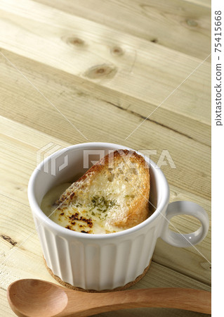 French onion soup and wooden spoon with charred French bread on cheese 75415668