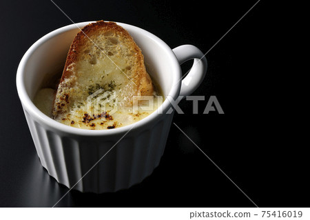 Shooting onion gratin soup to eat in a cup on a black background Shooting onion gratin soup to eat in a cup on a black background 75416019