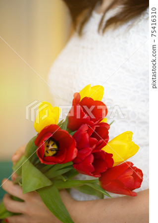 Soft focus of anonymous female carrying bunch of colorful fresh tulips during holiday celebration in spring Soft focus of anonymous female carrying bunch of colorful fresh tulips during holiday celebration in spring 75416310