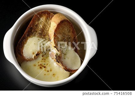 Photographed onion soup with charred cheese and French bread on a black background (overhead view) Photographed onion soup with charred cheese and French bread on a black background (overhead view) 75416508