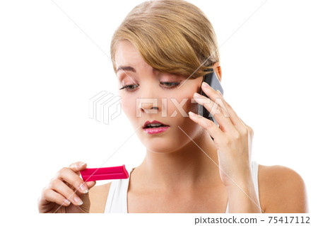Worried woman with phone informing someone about positive pregnancy test 75417112