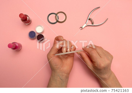 Woman Hands Filing Nails. Gives himself a manicure. Elderly hands. Pink background. Woman Hands Filing Nails. Gives himself a manicure. Elderly hands. Pink background. 75421163