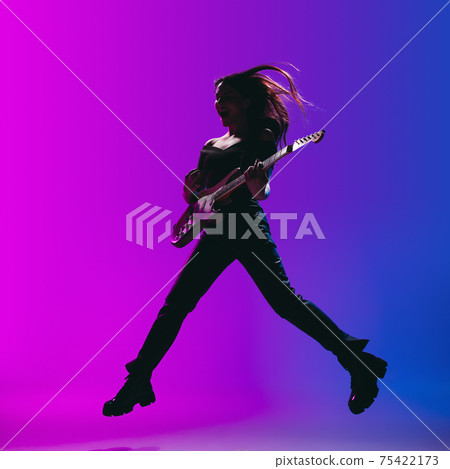 Silhouette of young female guitarist isolated on gradient background in neon. 75422173