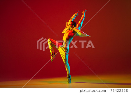Young male dancer dancing hip-hop isolated over red background in neon light 75422338