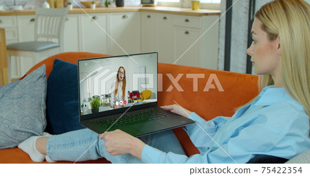 Female student is studies by internet video lesson with teacher using laptop at Home. E-learning Classe or Webinar at COVID-19 Pandemic. 75422354